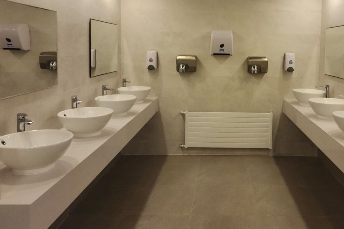 Baños remodelados del Centro de Eventos, con lavamanos de sobreponer sobre cubierta blanca y espejos